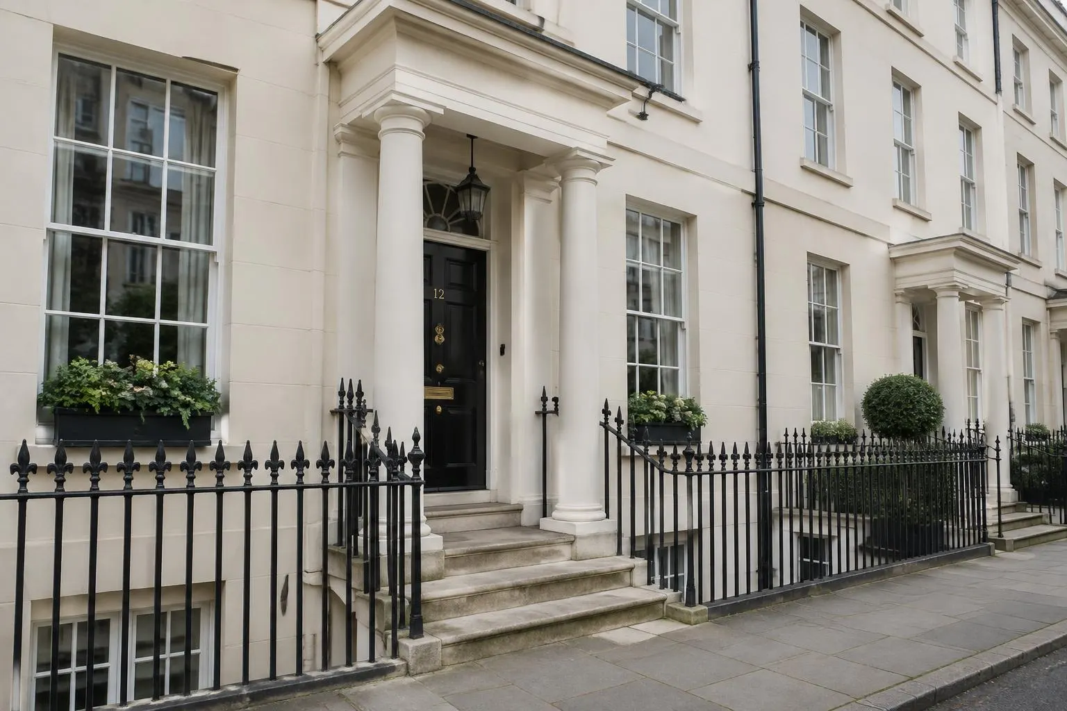 Cream stucco Regency terrace with tall sash windows, a pillared porch and black railings