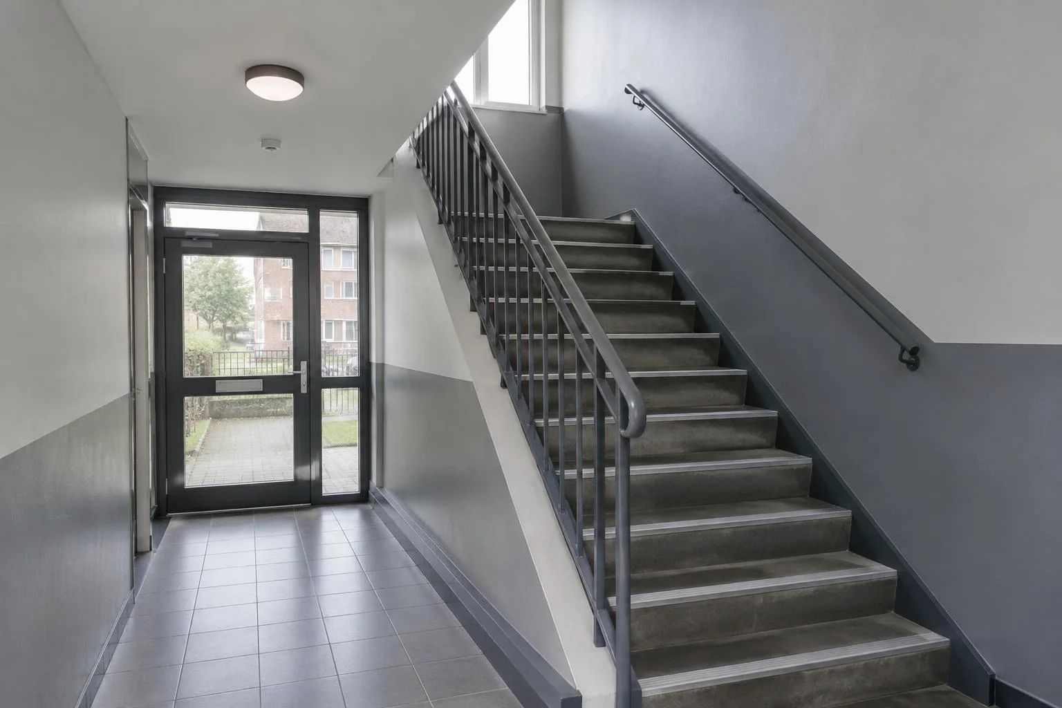 Communal stairwell with grey lower walls and metal handrails