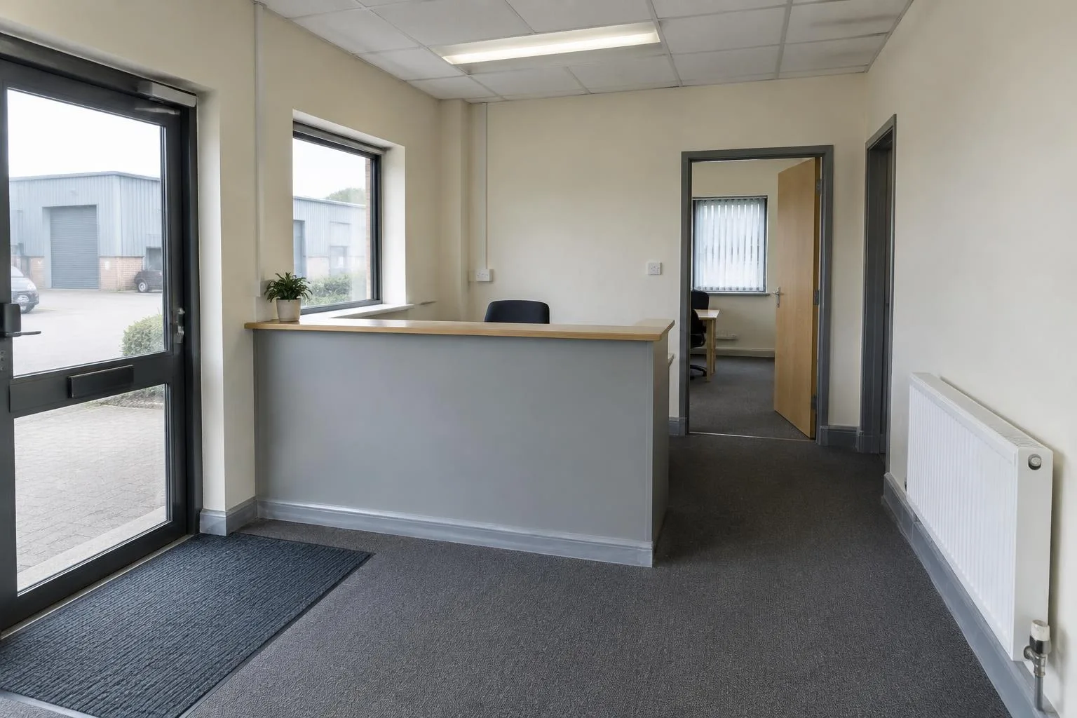 Small office reception with a counter and windows overlooking industrial buildings